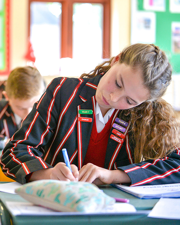 Year 6 girl pupil writing in class. Castle Court School, Corfe Mullen, Wimborne, Dorset