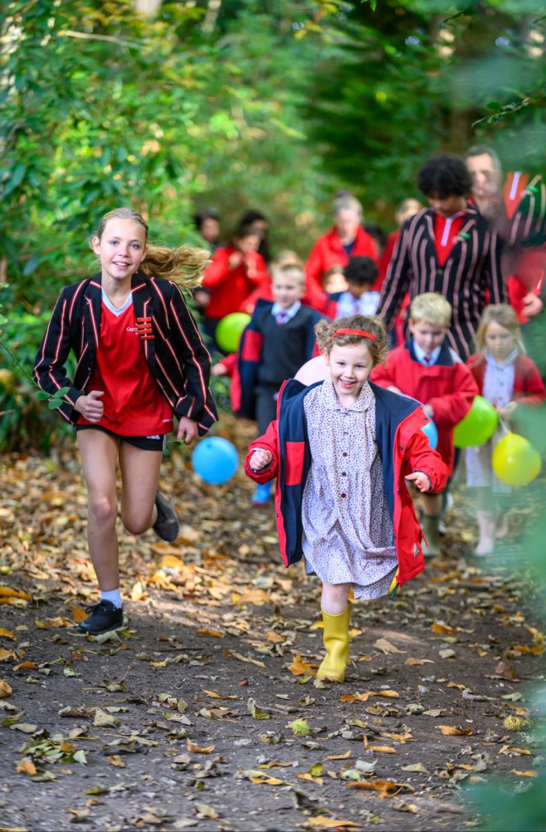 a group of students running on a woodland path