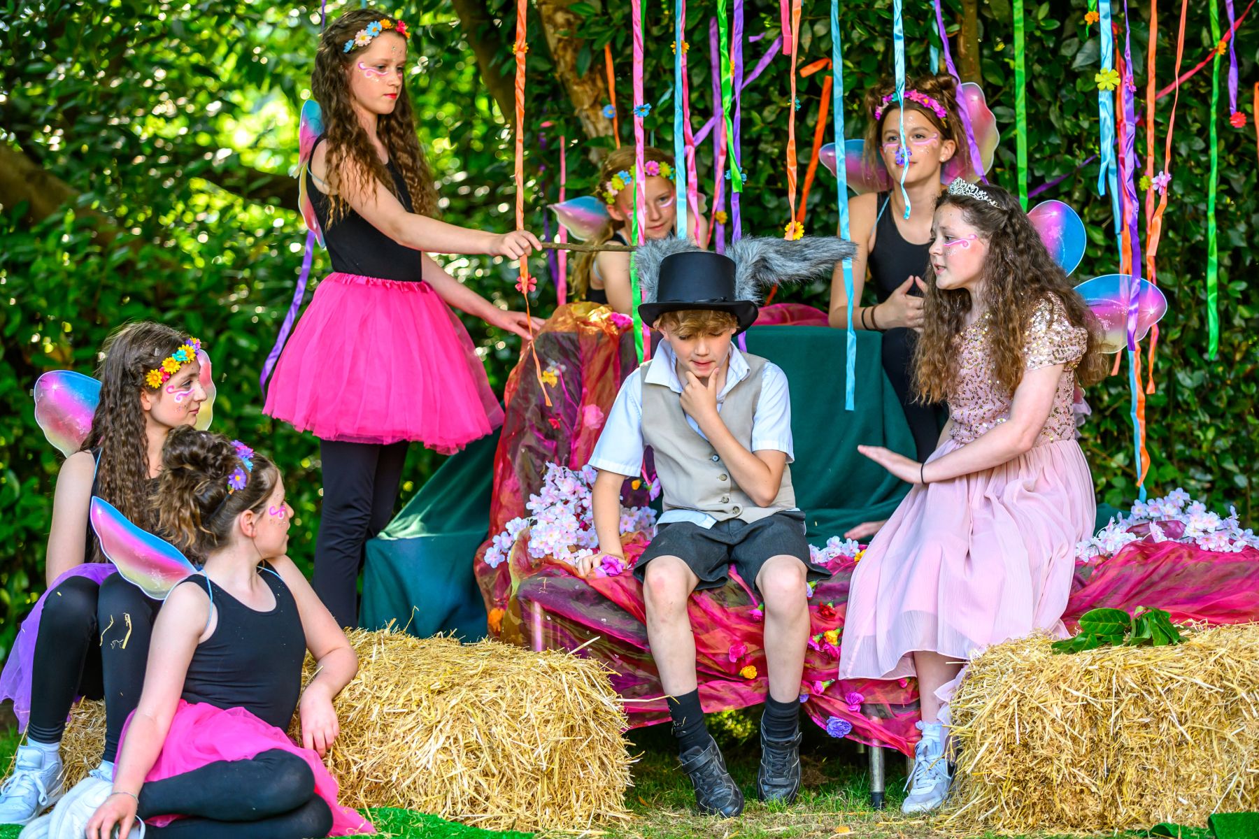 Students in fairy and character costumes performing an outdoor school play