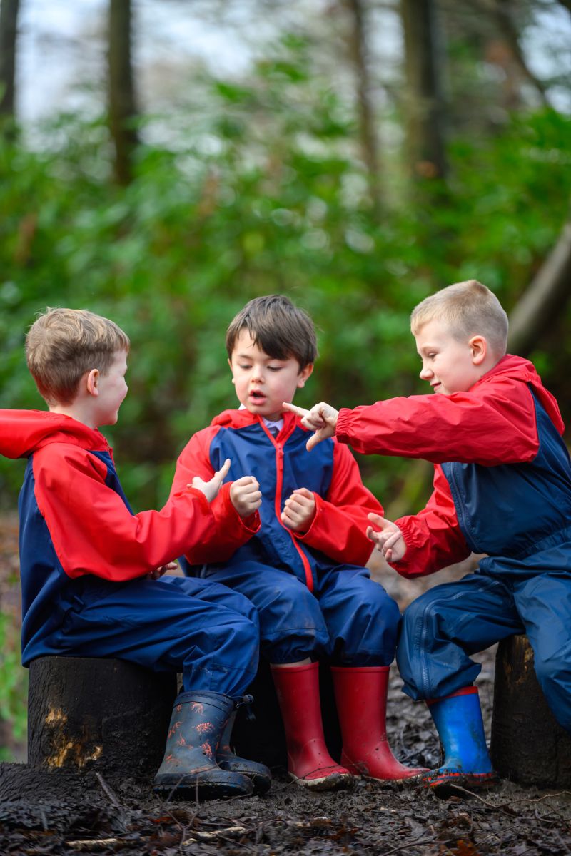 photo of three students playing in the woodland