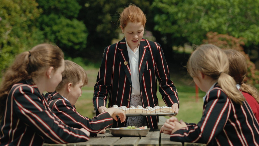 A student in a school uniform holding a lunch plate in the dining hall.