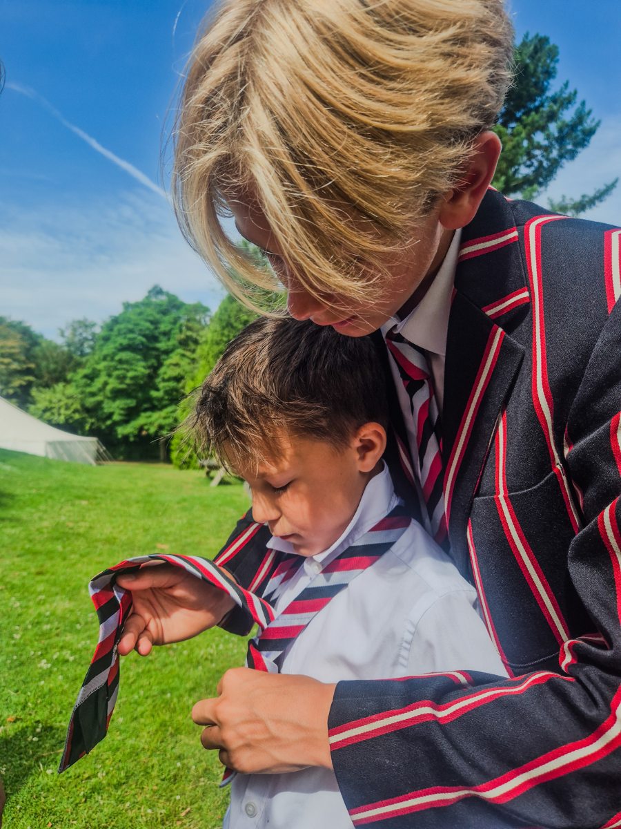 student helping another student to tie his tie