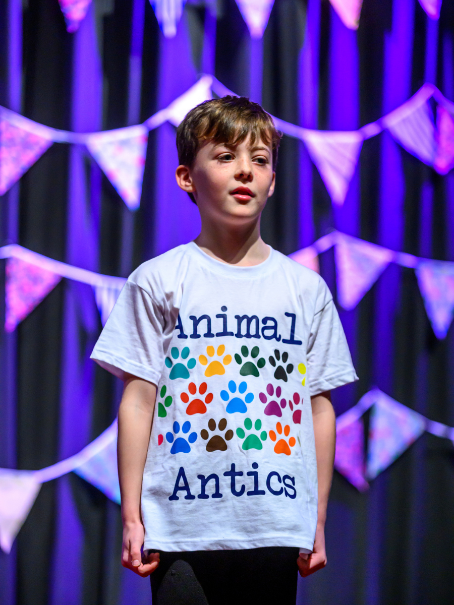 a photo of a student standing on stage wearing an animal antics t shirt