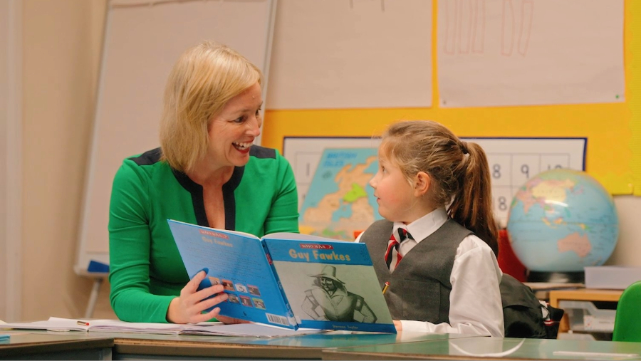 portrait of the school headteacher reading with a student